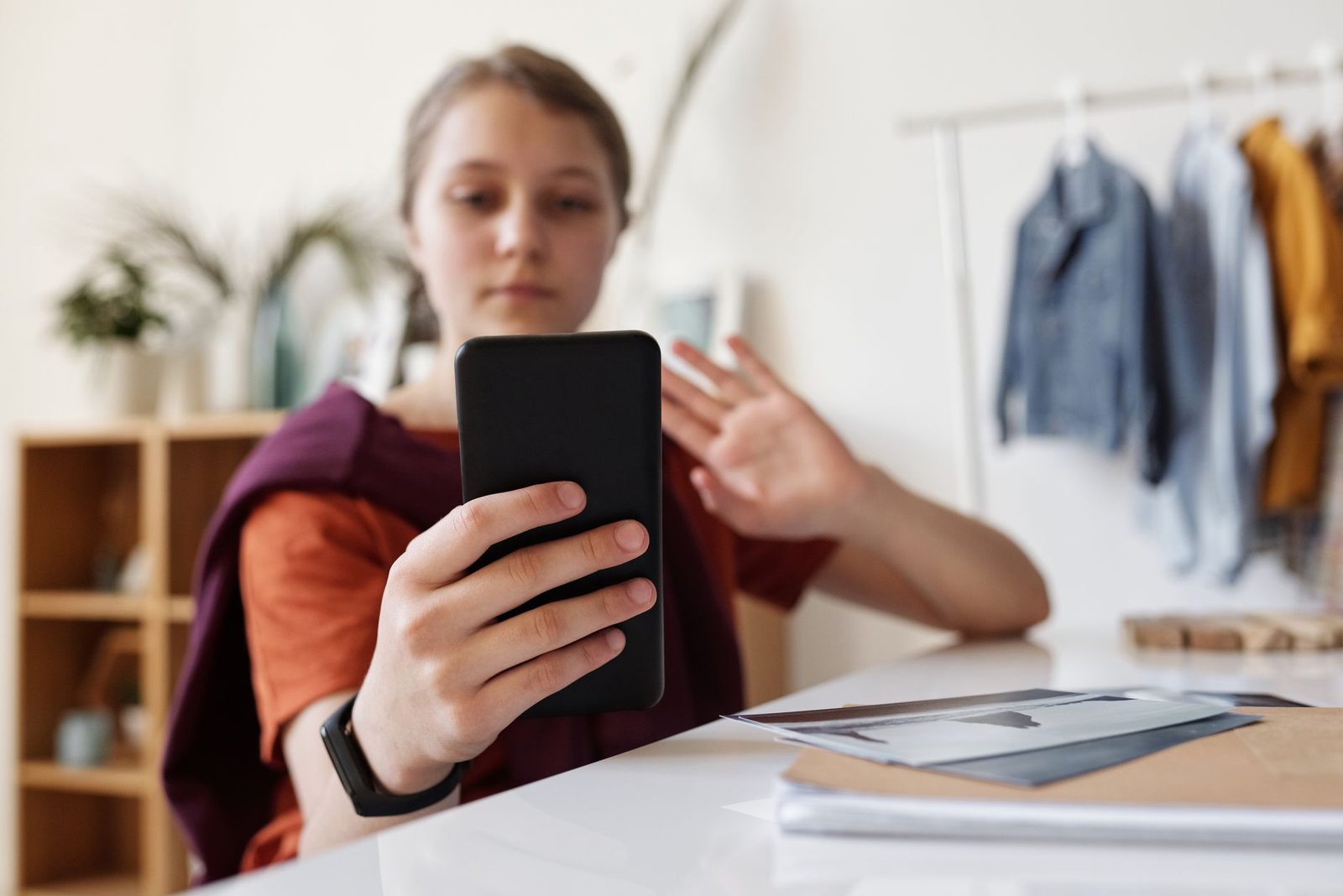 Akıllı telefonunu tutup görüntülü görüşme sırasında el sallayan genç kadın