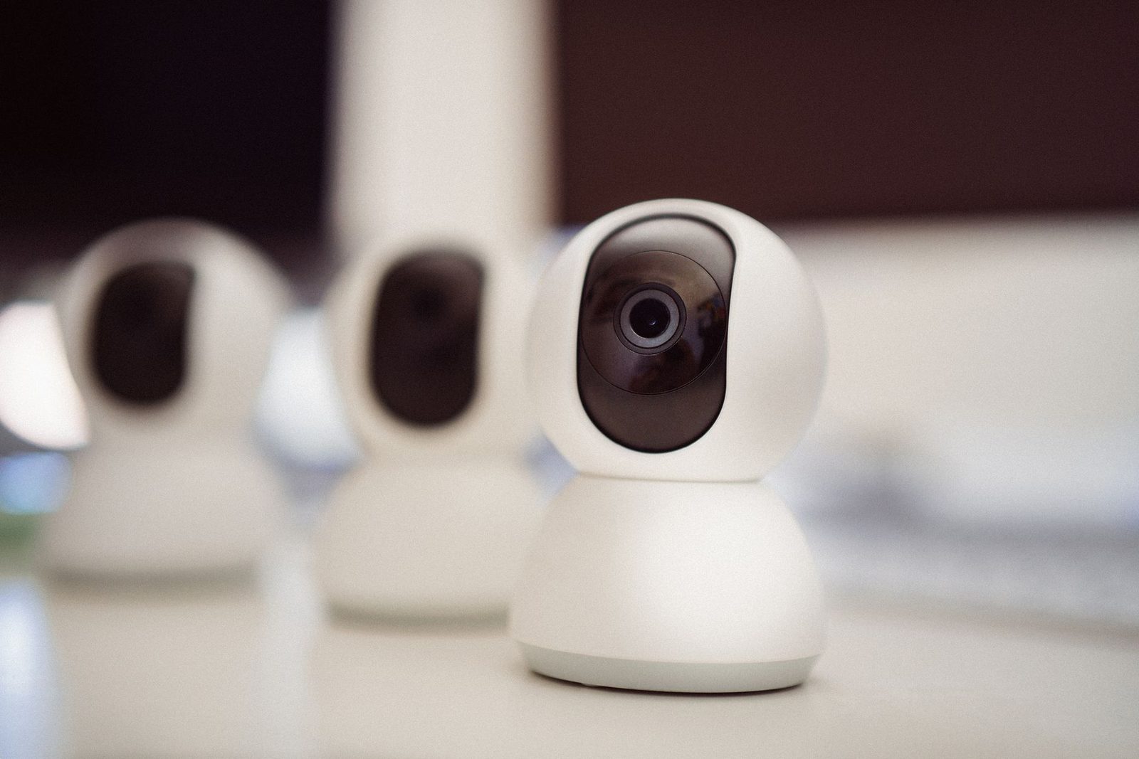 Drei weiße Webcams, die auf einer ebenen Fläche nebeneinander stehen, mit Fokus auf die Kamera im Vordergrund.